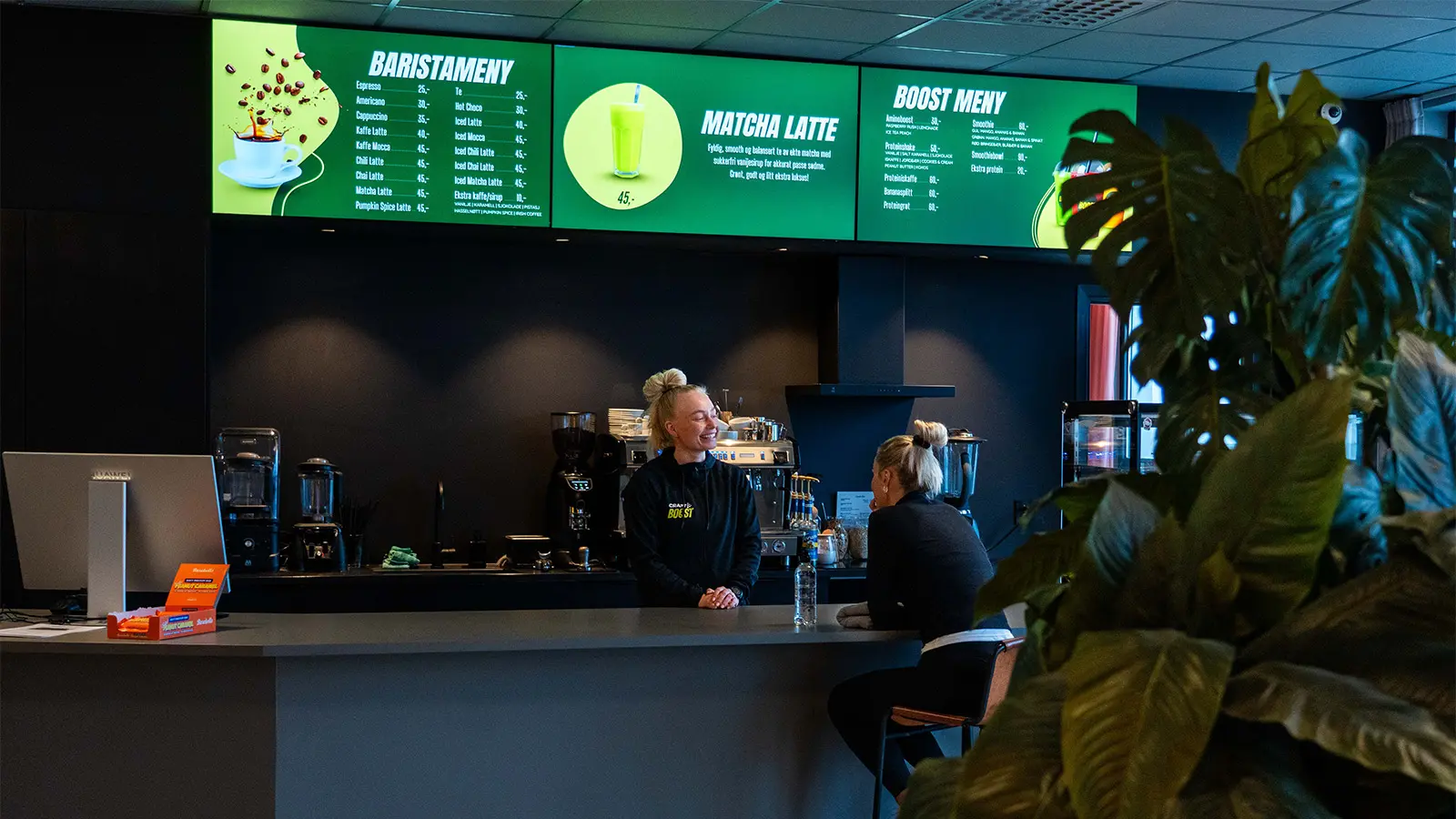Café area at Boost, where a row of digital menu boards displays products, menus and prices.