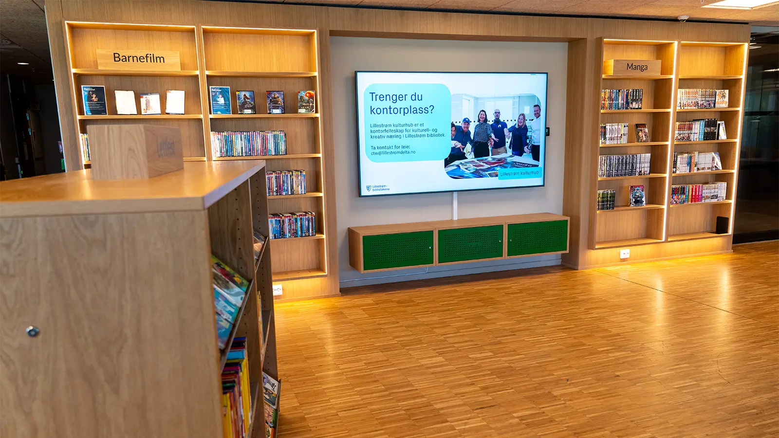 A large digital information screen positioned between two bookshelves.